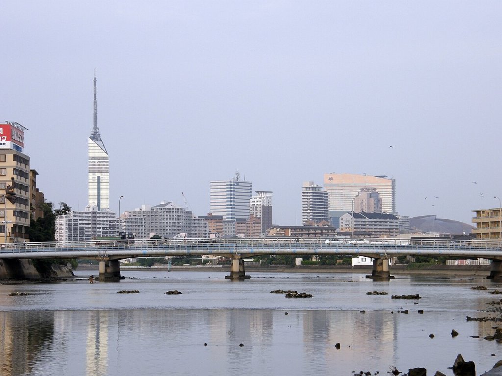 Fukuoka Tower and the city skyline seen across the Muromi River, with a bridge in front