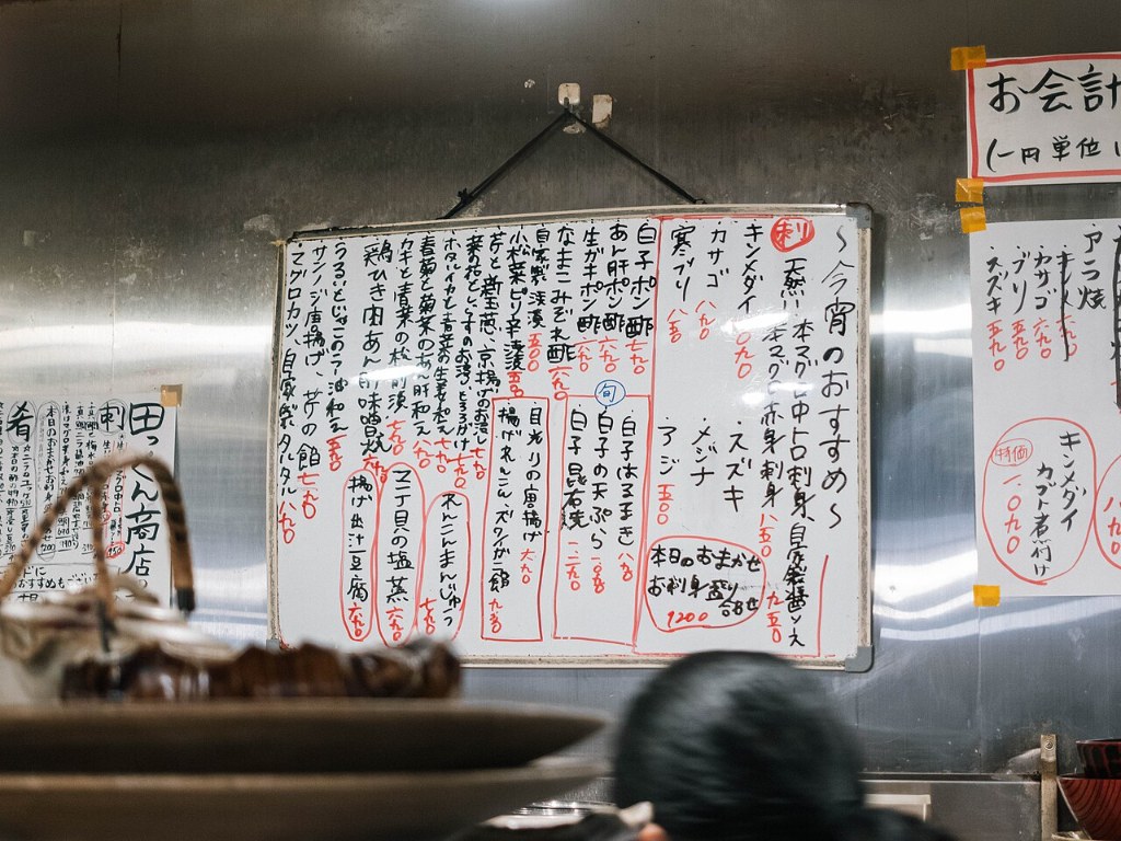 A handwritten menu of the day's recommendations on the wall of an izakaya