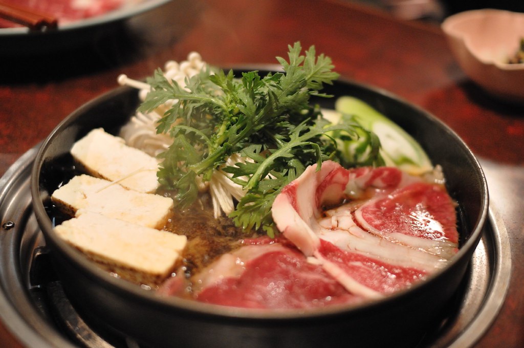 鉄鍋で煮えるすき焼き。牛肉、焼き豆腐、春菊、えのき